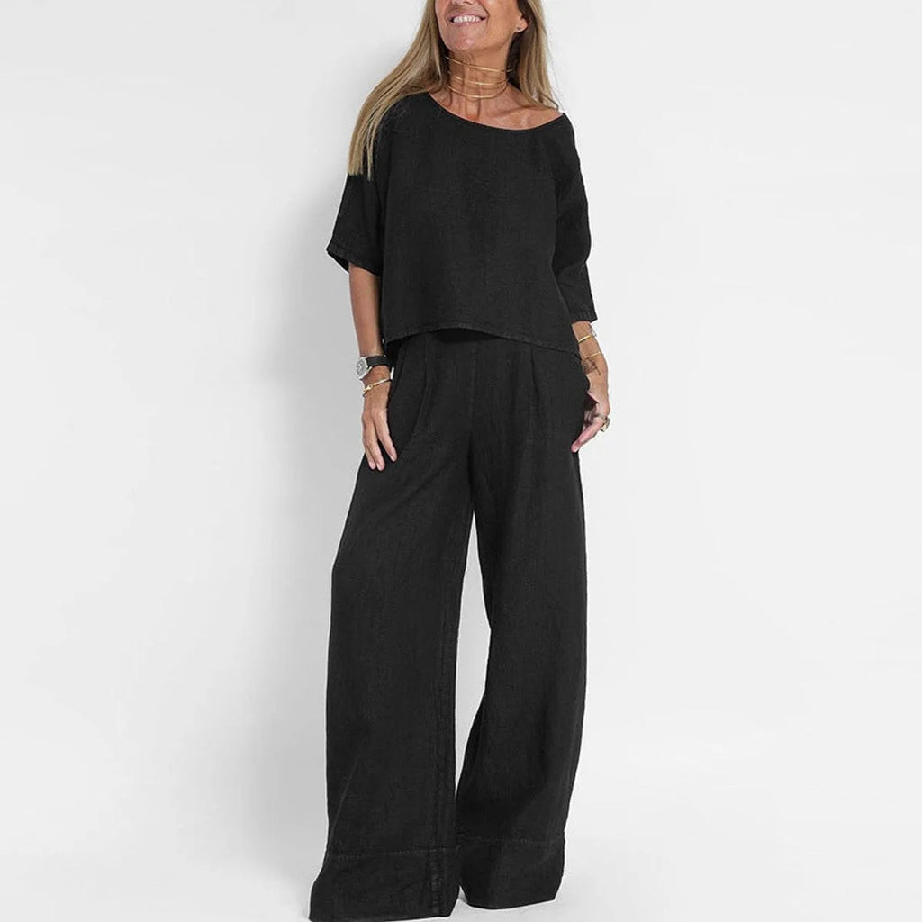 Woman wearing the two-piece set in black, showing the relaxed crop top and wide leg trousers with pleated waist