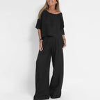 Woman wearing the two-piece set in black, showing the relaxed crop top and wide leg trousers with pleated waist