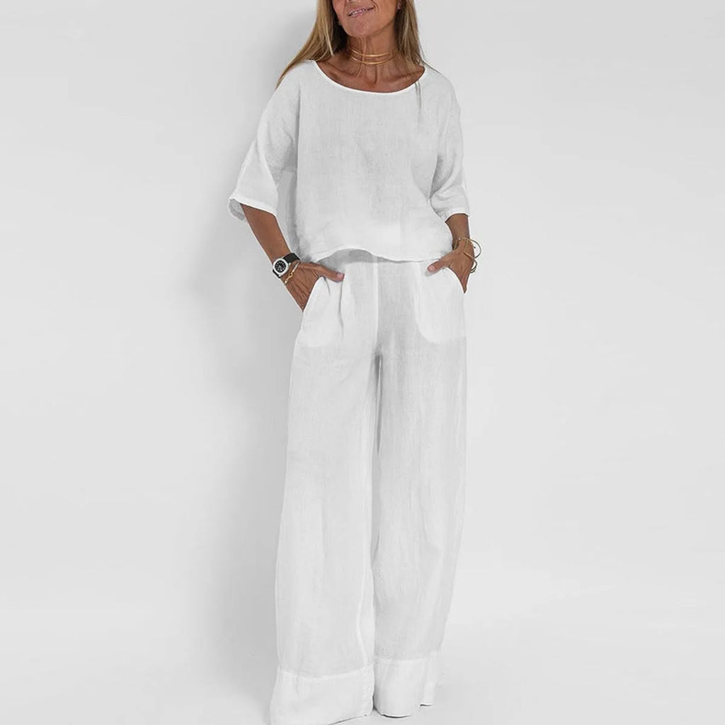 Woman wearing the two-piece set in white, boxy top with dropped shoulders and wide leg pants with turned-up hem