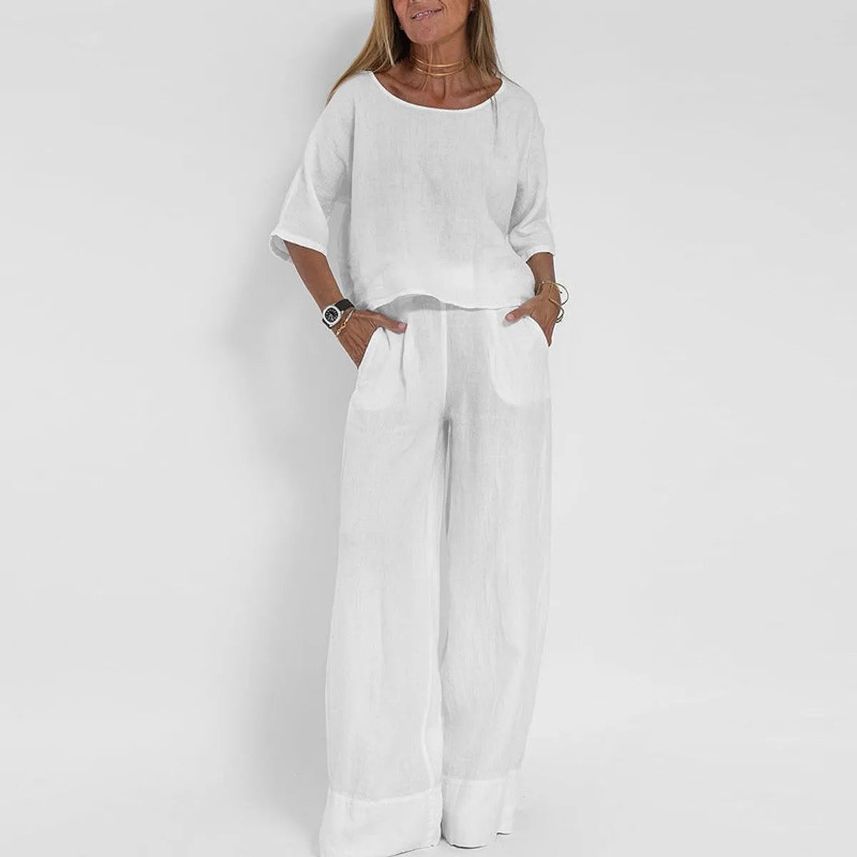 Woman wearing the two-piece set in white, boxy top with dropped shoulders and wide leg pants with turned-up hem