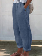Side profile of cream wide-leg pants worn with slide sandals, showing ankle-length cuffed hem