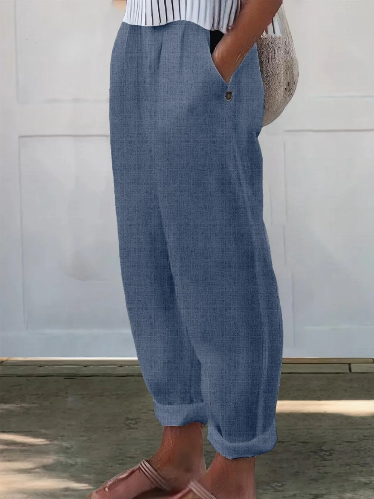 Side profile of cream wide-leg pants worn with slide sandals, showing ankle-length cuffed hem