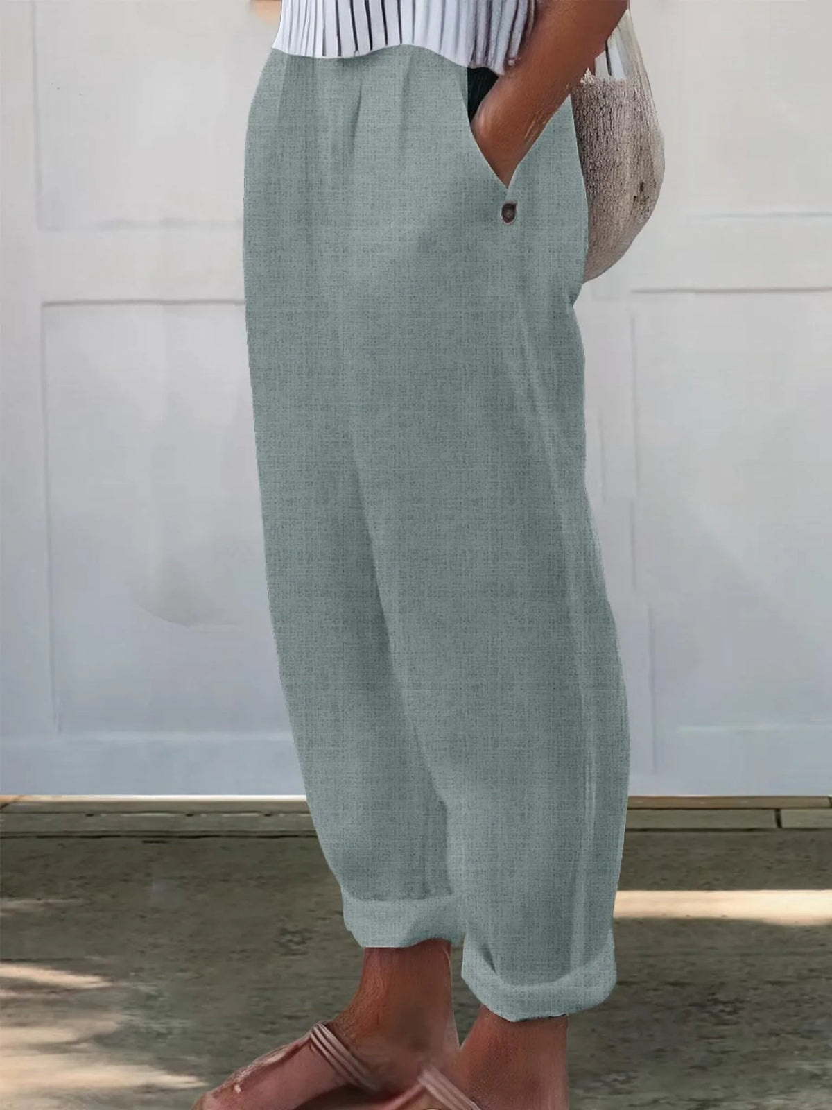 Side view of pale pink linen-look trousers highlighting the high waist and loose tapered leg