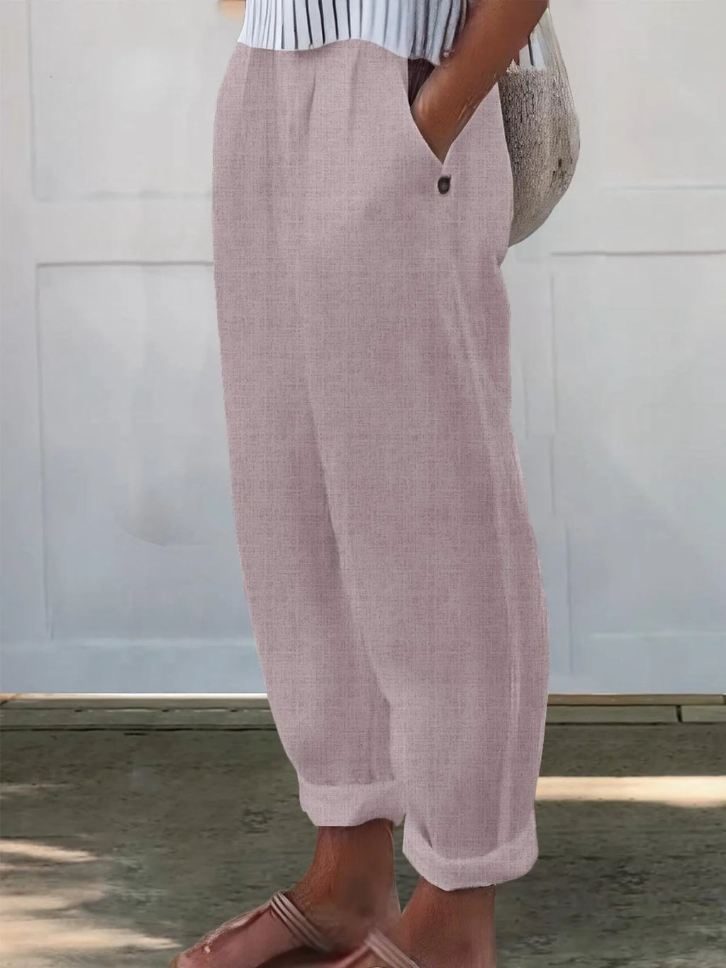 Side profile of pale pink wide-leg trousers with elastic waist and buttoned side pocket