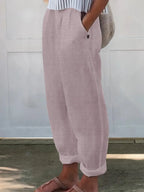 Side profile of pale pink wide-leg trousers with elastic waist and buttoned side pocket