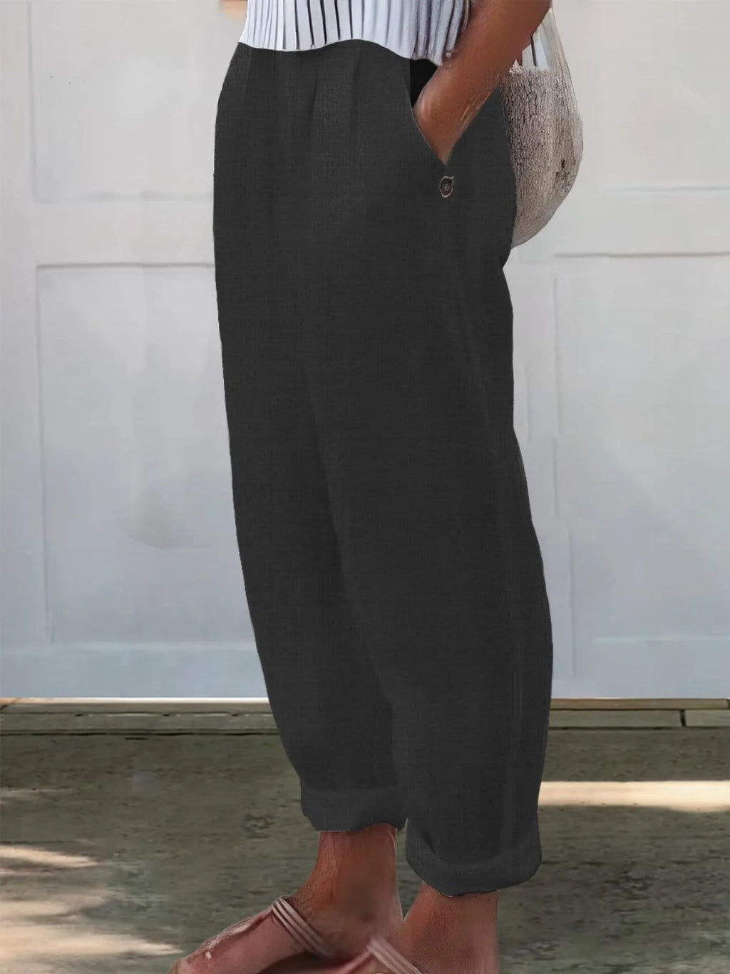 Side view of charcoal black wide-leg pants highlighting the loose silhouette and rolled cuff hem