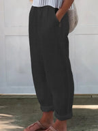 Side view of charcoal black wide-leg pants highlighting the loose silhouette and rolled cuff hem