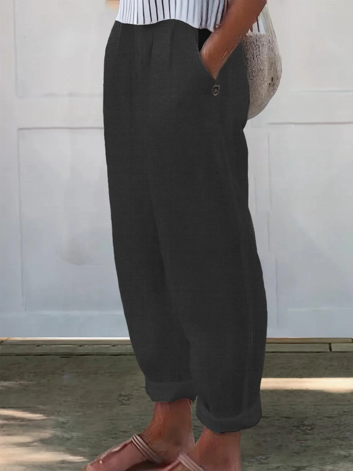 Side view of charcoal black wide-leg pants highlighting the loose silhouette and rolled cuff hem