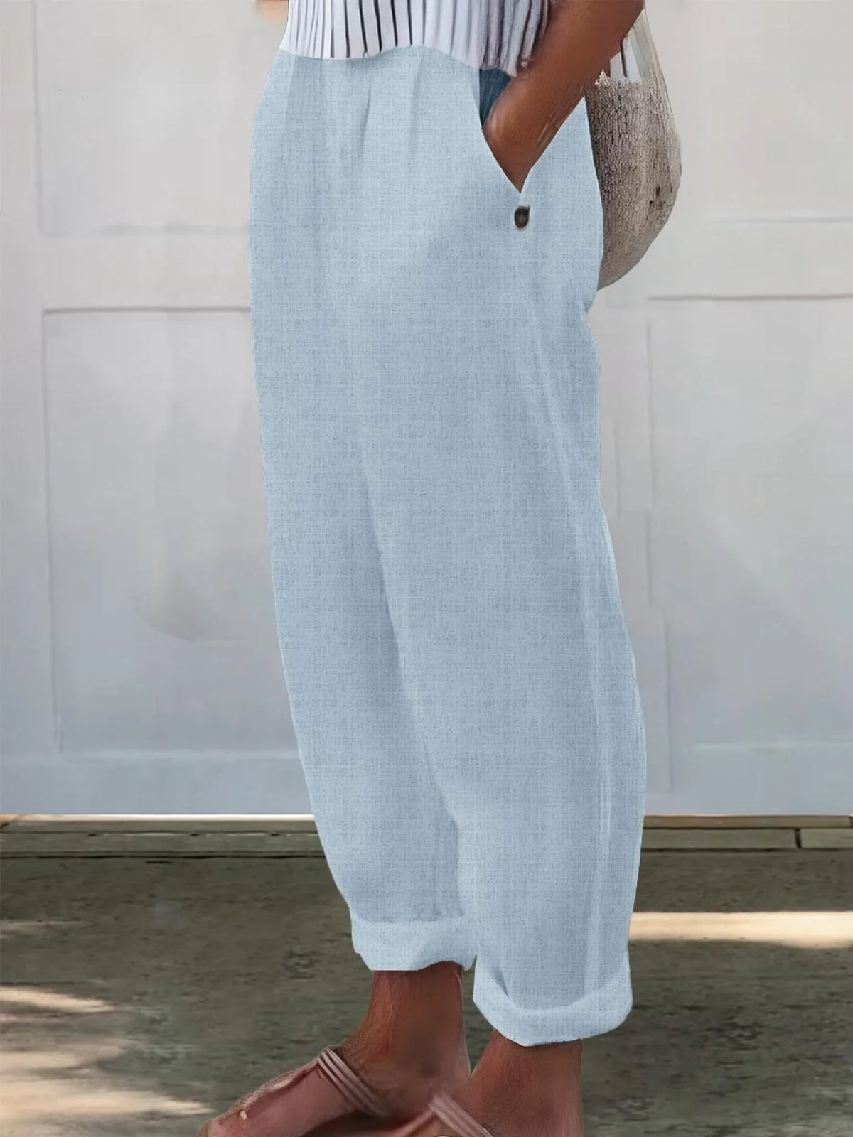 Side profile of pale sky blue linen-look trousers with side pocket and folded ankle cuff