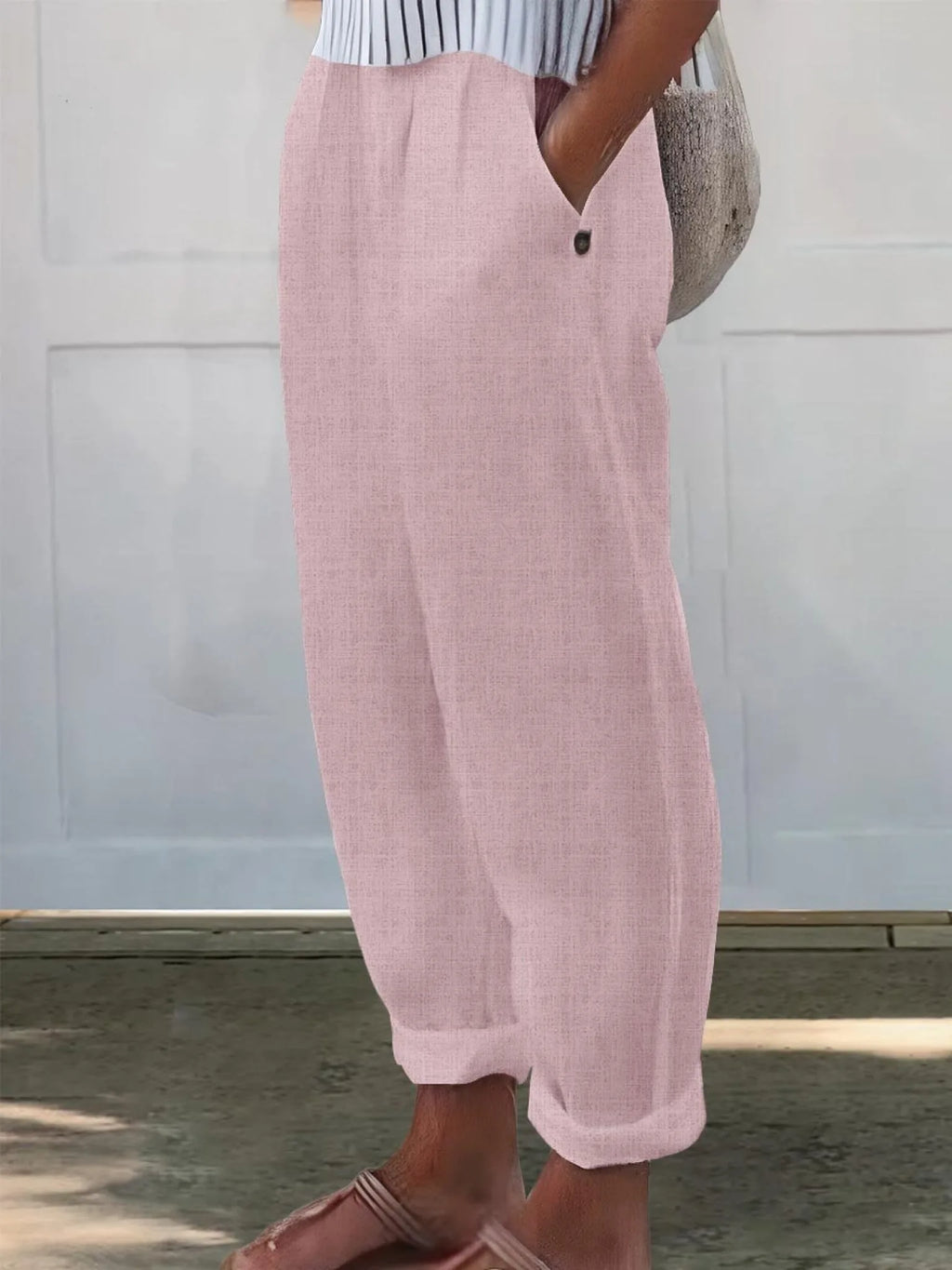 Close-up side view of soft pink wide-leg pants showing fabric texture and button pocket closure