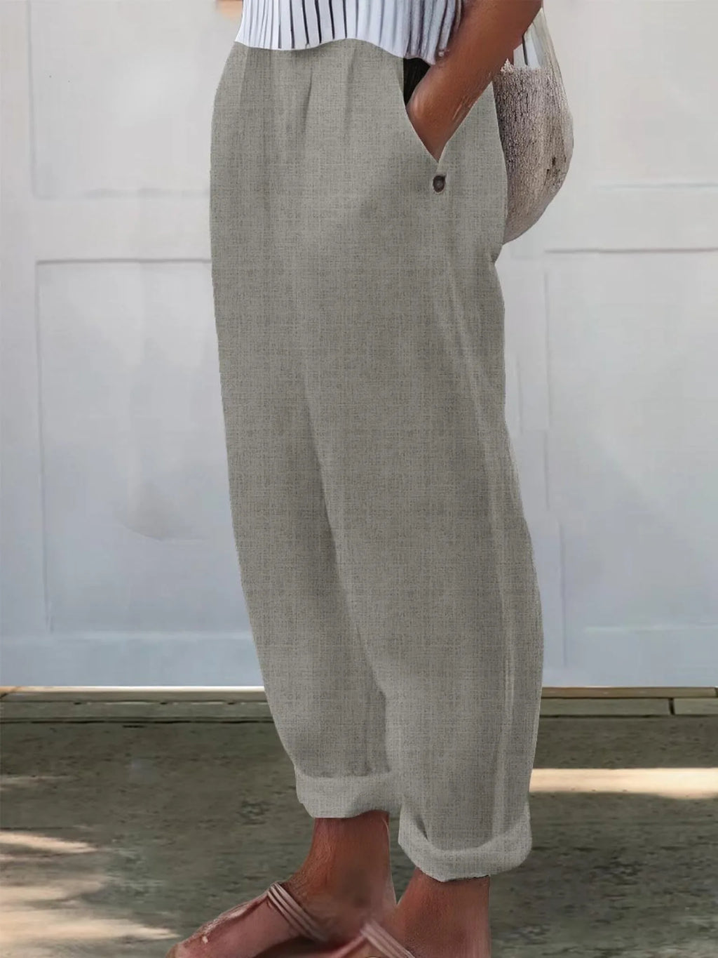 Side view of light taupe grey wide-leg trousers with elasticated waistband and tapered rolled hem
