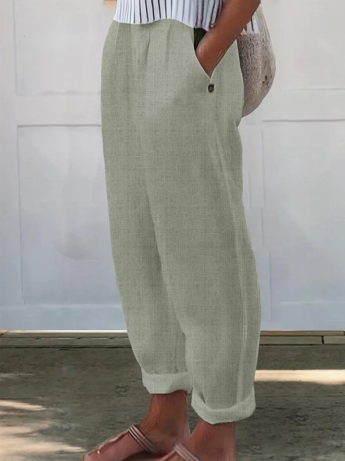 Side profile of sage green wide-leg pants showing relaxed fit and buttoned pocket opening