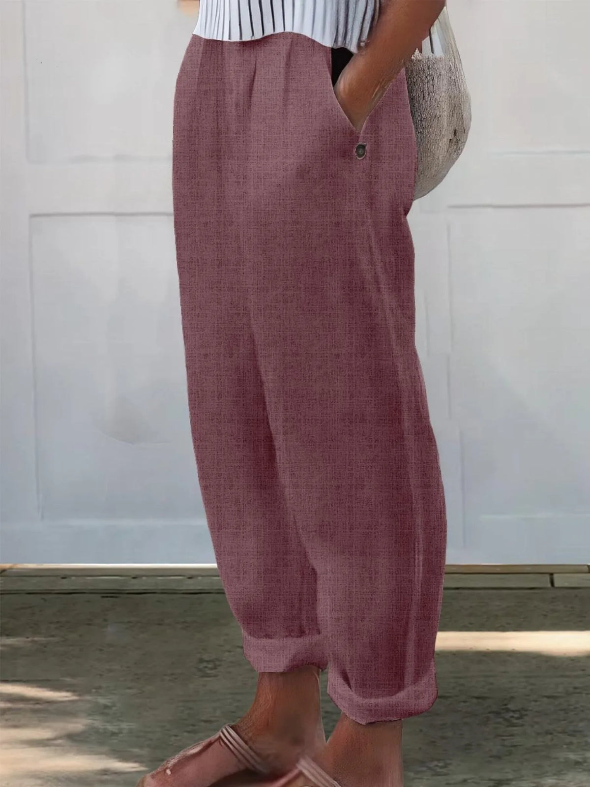 Side view of white wide-leg trousers styled with a striped top and woven tote bag