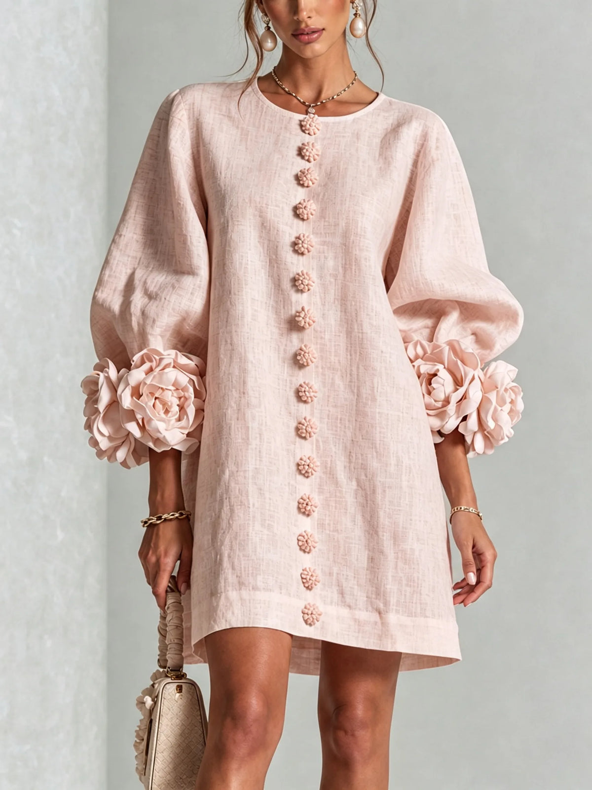 Close-up of the oversized 3D fabric flower detail on the sleeve cuff of the white dress