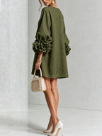 Front view of the white textured mini dress with round neckline, long voluminous sleeves and floral cuffs