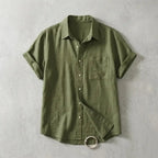 Olive green linen short-sleeve shirt with chest pocket, shown flat with sleeve folded open to reveal hem detail