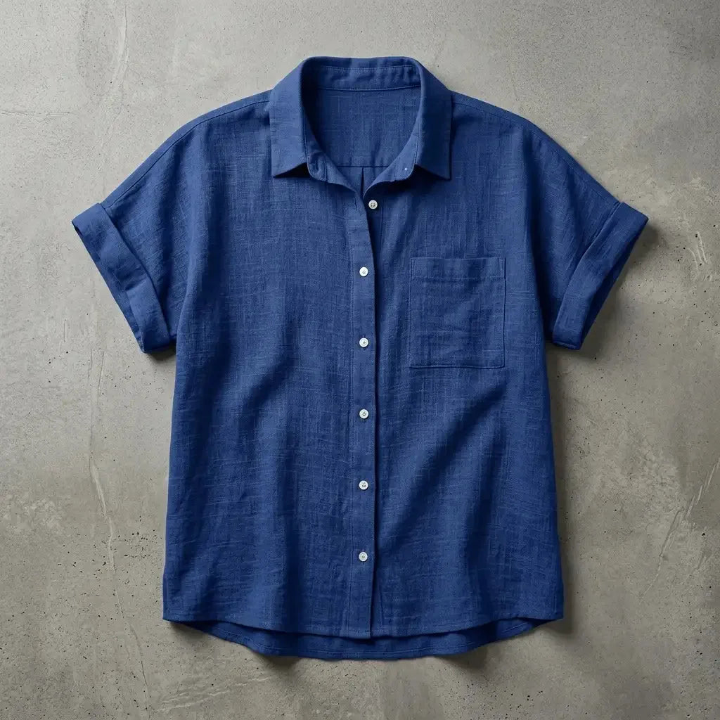 Navy blue linen short-sleeve shirt with chest pocket, buttoned and laid flat against a stone-grey backdrop