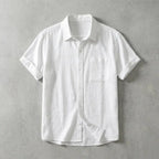 White linen short-sleeve shirt with chest pocket and rolled sleeves, laid flat with one cuff folded back