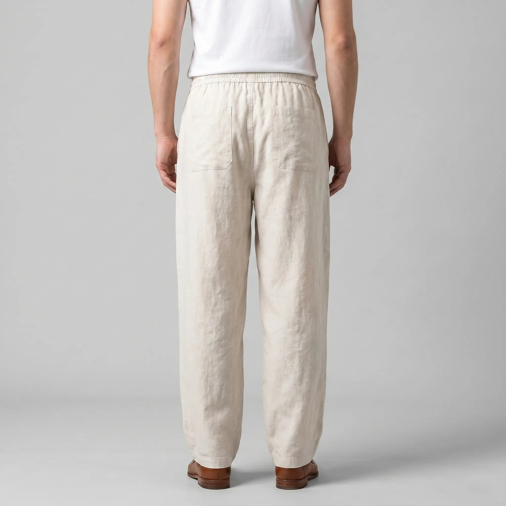 Back view of the beige linen pants showing the relaxed fit, back pocket and straight hem falling above the shoes