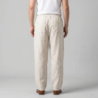 Back view of the beige linen pants showing the relaxed fit, back pocket and straight hem falling above the shoes