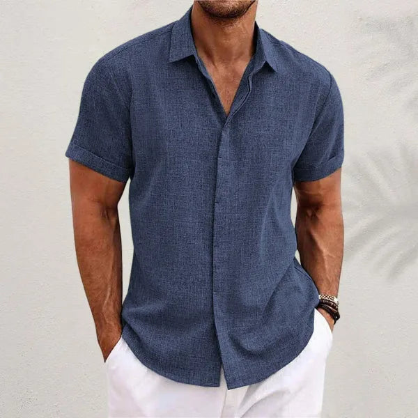 Close view of a navy blue short-sleeve shirt with classic collar and button placket, worn with white trousers