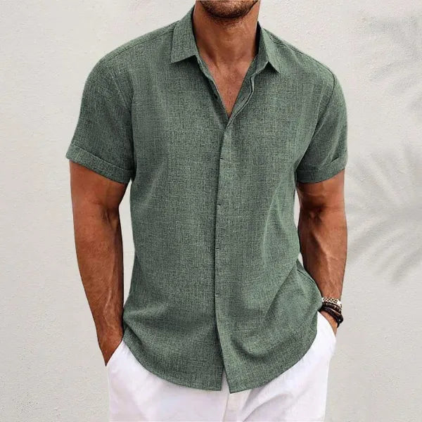 Army green short-sleeve shirt with a textured weave, rolled sleeves and button-up front against a plain wall