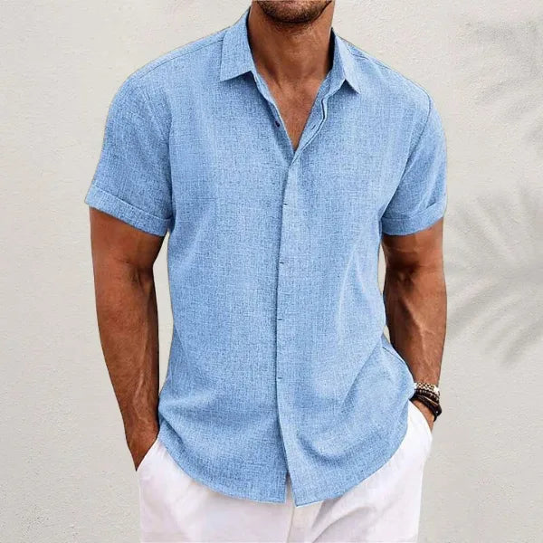 Light blue short-sleeve shirt with visible woven texture, open collar and rolled cuffs, studio shot