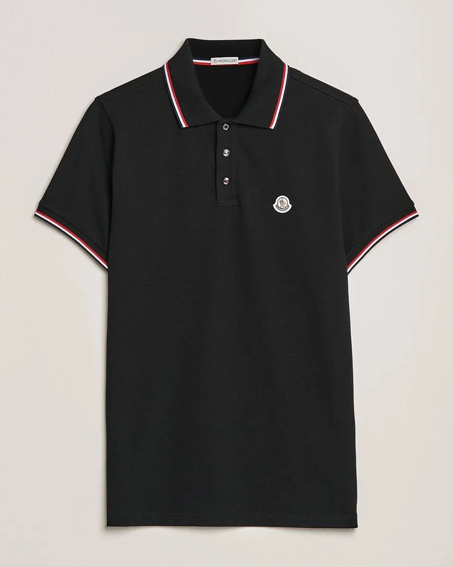 Black polo shirt with ribbed red, white and navy tipped collar and cuffs, logo patch on chest, laid flat