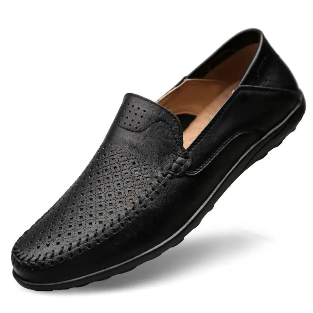 Angled view of a black perforated leather loafer showing the hand-stitched vamp and tan leather lining