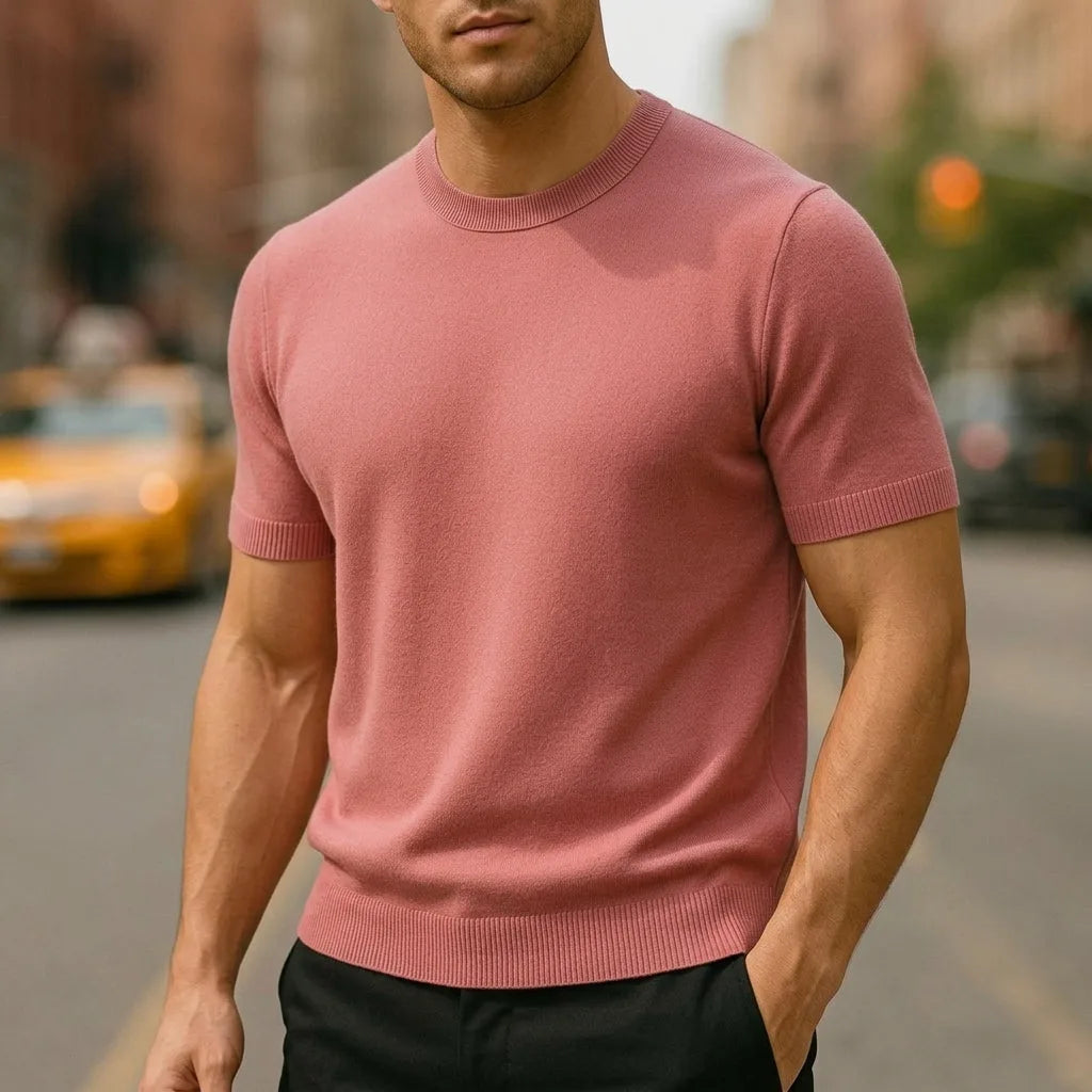 Close-up of a dusty pink short-sleeve knitted T-shirt with ribbed crew neck and cuffs on a city street
