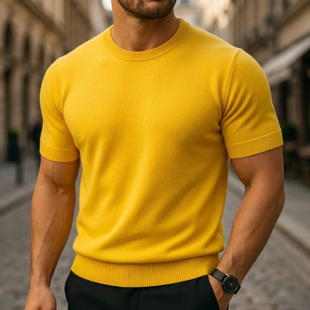 Man wearing a mustard yellow short-sleeve knit T-shirt with ribbed hem on a cobblestone street