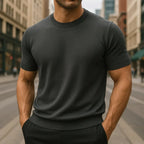 Man in a dark grey short-sleeve knitted T-shirt with ribbed neckline standing on a city road