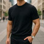 Close-up of a black short-sleeve knitted T-shirt with ribbed crew neck and cuffs, paired with a wristwatch