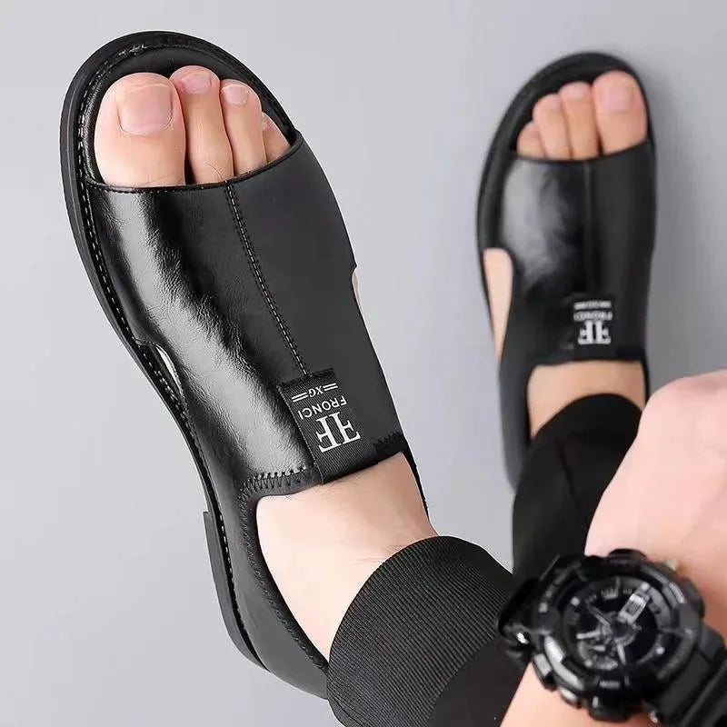 Close-up of black leather sandals worn barefoot, showing open toe and ankle strap stitching.