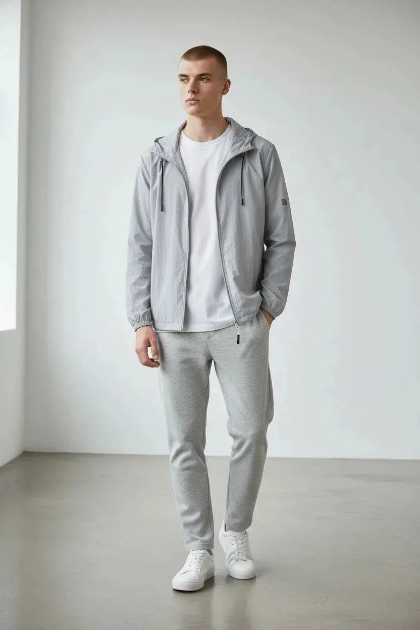 Full front view of the grey hooded windbreaker jacket worn open over a white tee with grey trackpants and sneakers.