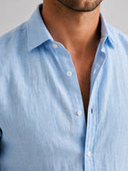 Close-up of the light blue linen-look shirt collar and button placket showing the woven texture of the fabric