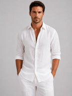 Man wearing a crisp white linen-look button-up shirt with rolled sleeves, styled with matching white trousers