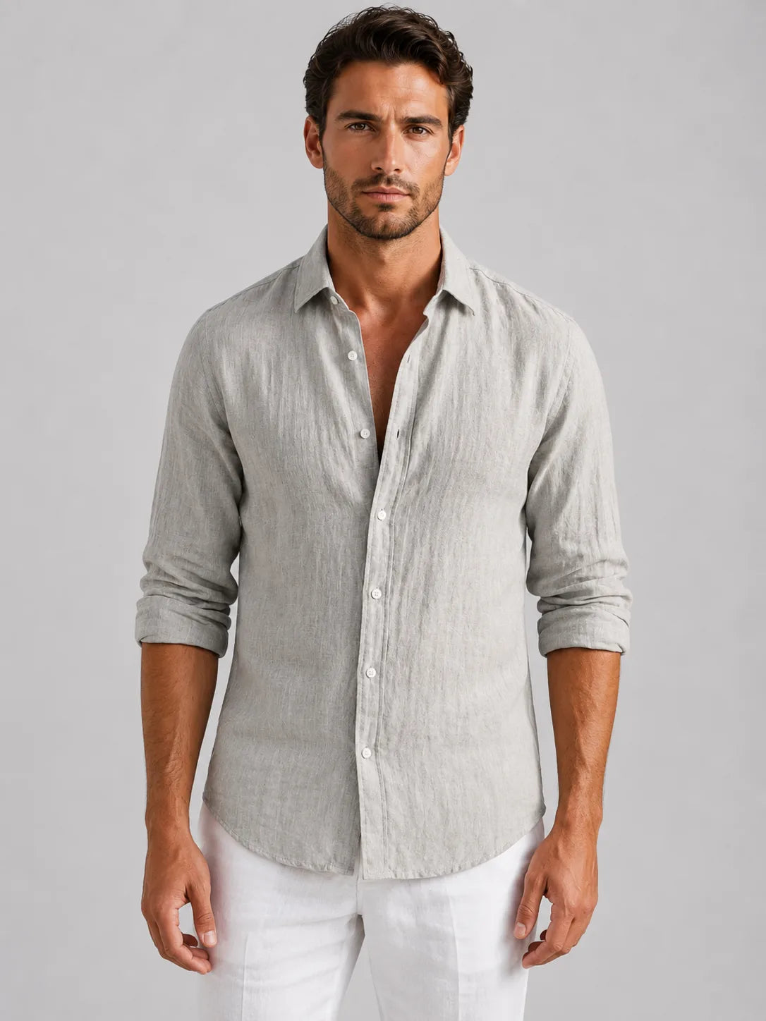 Man wearing a light grey linen-look button-up shirt with rolled sleeves, buttoned down over white trousers