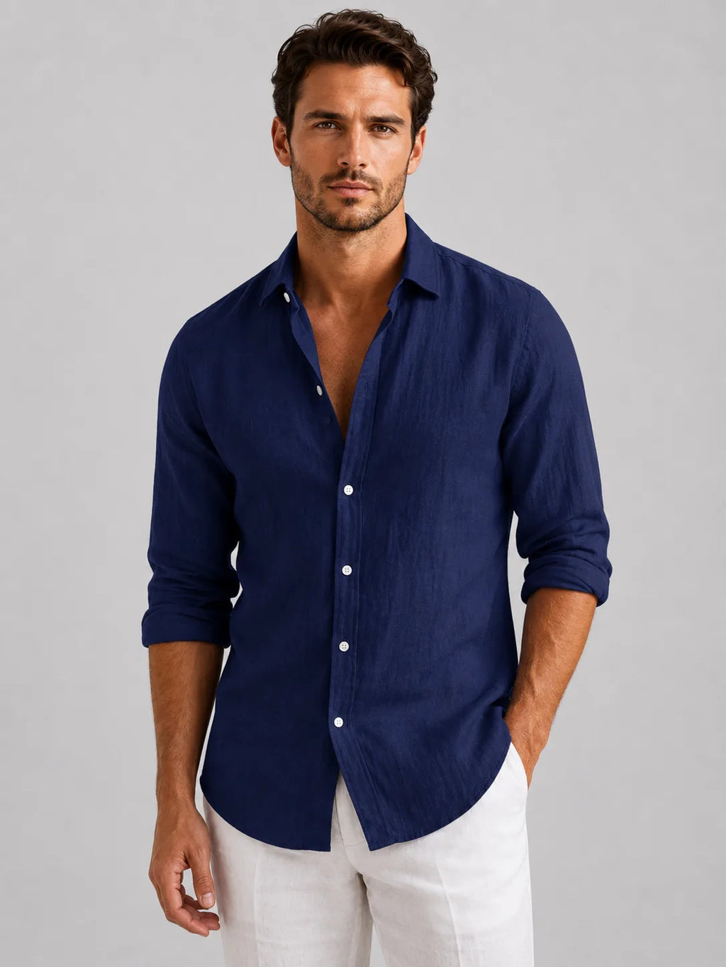 Man wearing a navy linen-look button-up shirt with rolled sleeves, buttoned over white trousers, front view
