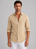 Man wearing a beige linen-look button-up shirt with rolled sleeves, buttoned down over white trousers