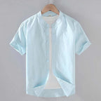 Powder blue linen short sleeve shirt on a hanger with cuffed sleeves and button front detail