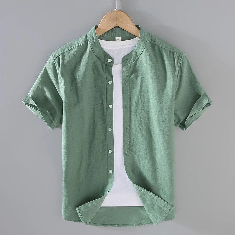 Sage green linen short sleeve shirt on a hanger with cuffed short sleeves and button placket