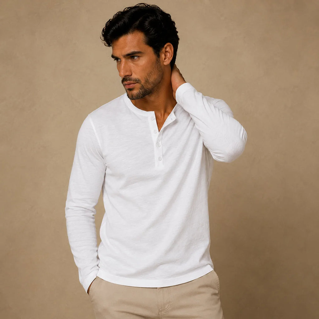 Man wearing white henley shirt with sleeve rolled slightly, hand behind neck, beige chinos