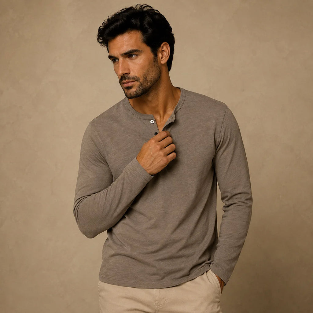 Man wearing khaki brown henley shirt, holding collar open, paired with beige chinos