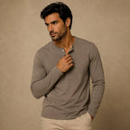 Man wearing khaki brown henley shirt, holding collar open, paired with beige chinos