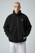 Front view of black textured sherpa fleece jacket with stand collar, full zip and chest logo badge