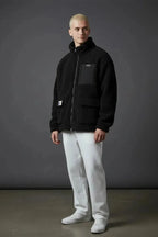 Full length view of black sherpa zip jacket styled with white pants and white sneakers