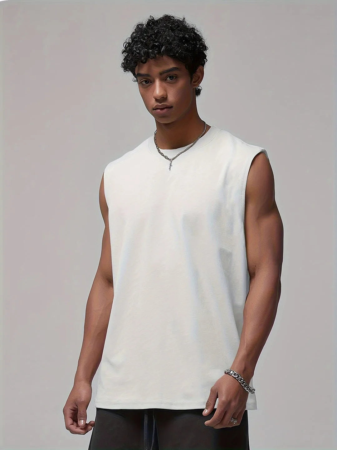 Front view of a man wearing a white sleeveless crew neck tank top with black shorts and a silver chain necklace