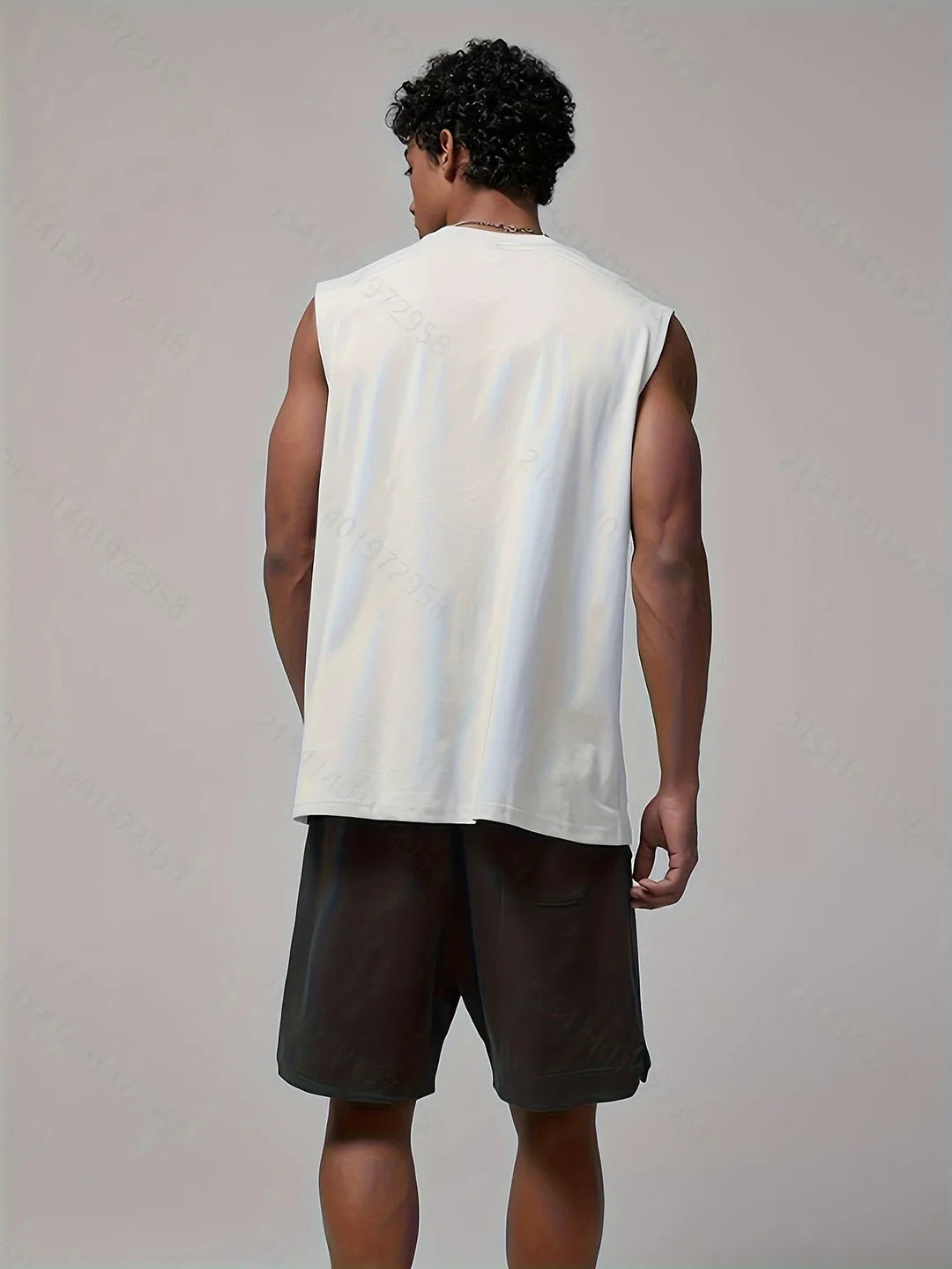 Back view of a man wearing a white sleeveless tank top with black shorts, showing the relaxed drop-shoulder cut