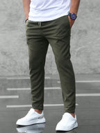 Back view of army green slim fit chino pants with drawstring waist, styled with white sneakers and a plain white t-shirt.